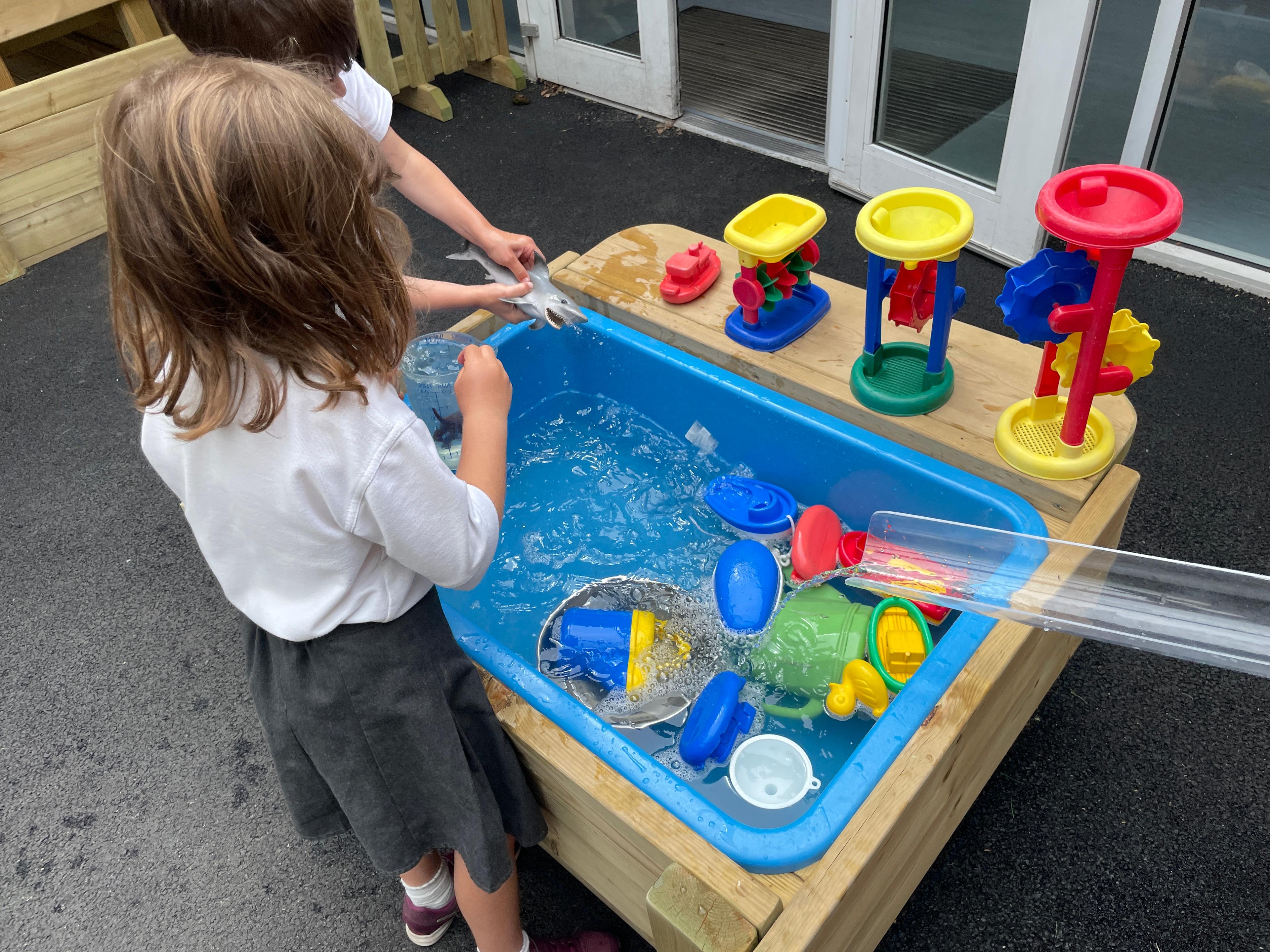Children playing with water toys in the water table which is part of the Windermere water play package