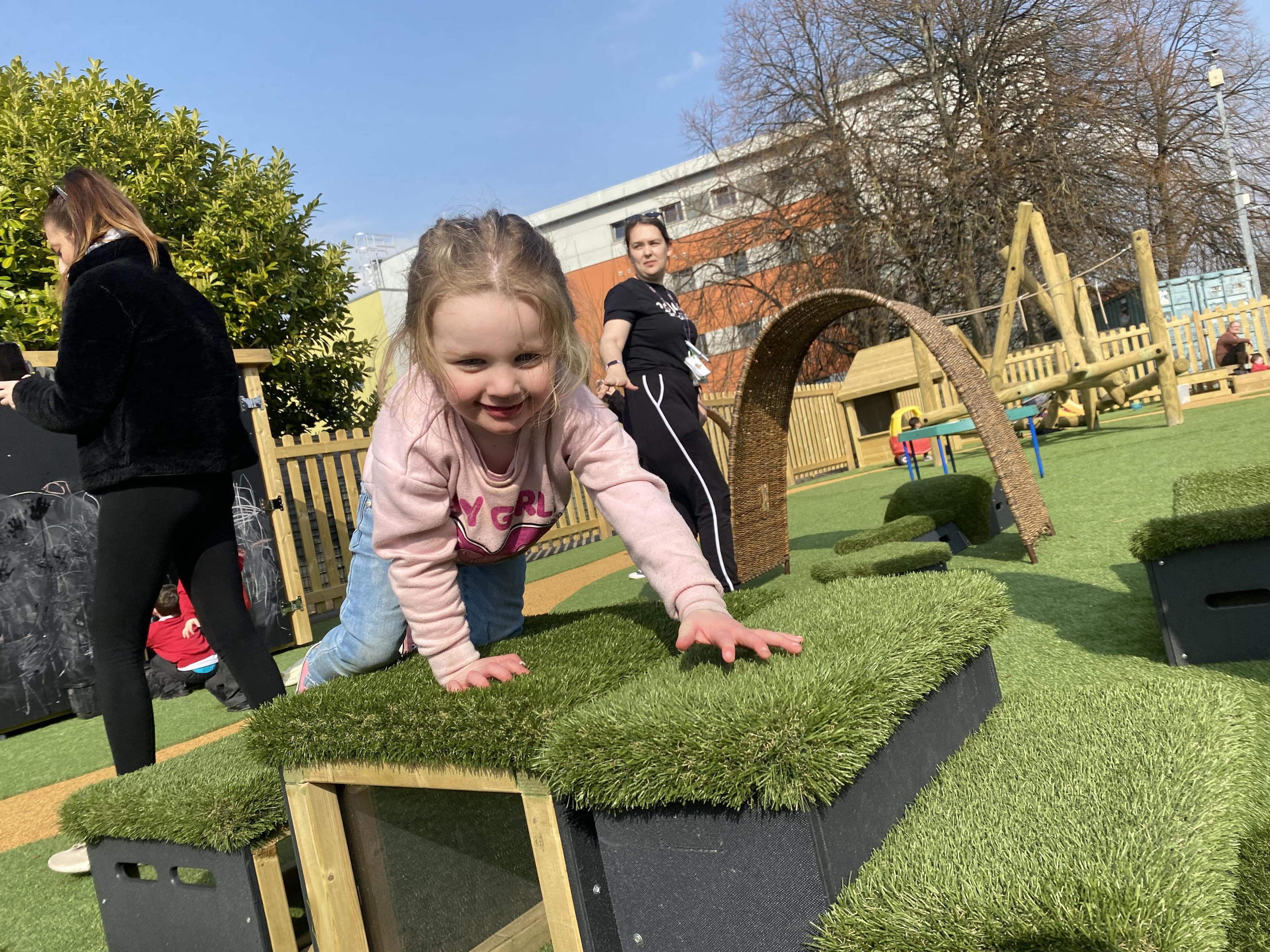 A little girl is crawling over the top of some Get Set Go Blocks.