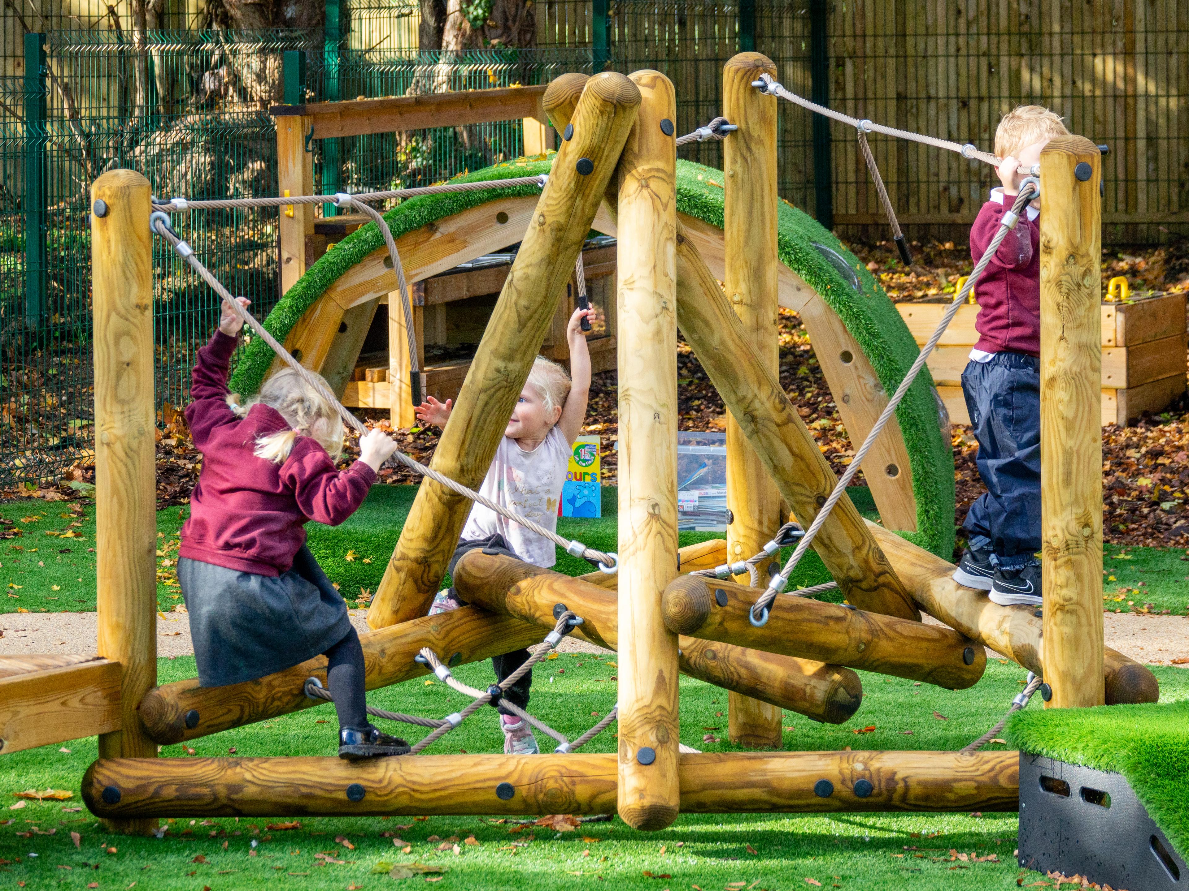 A group of children playing on the Pinnacle Hill Climber with platform in the playground