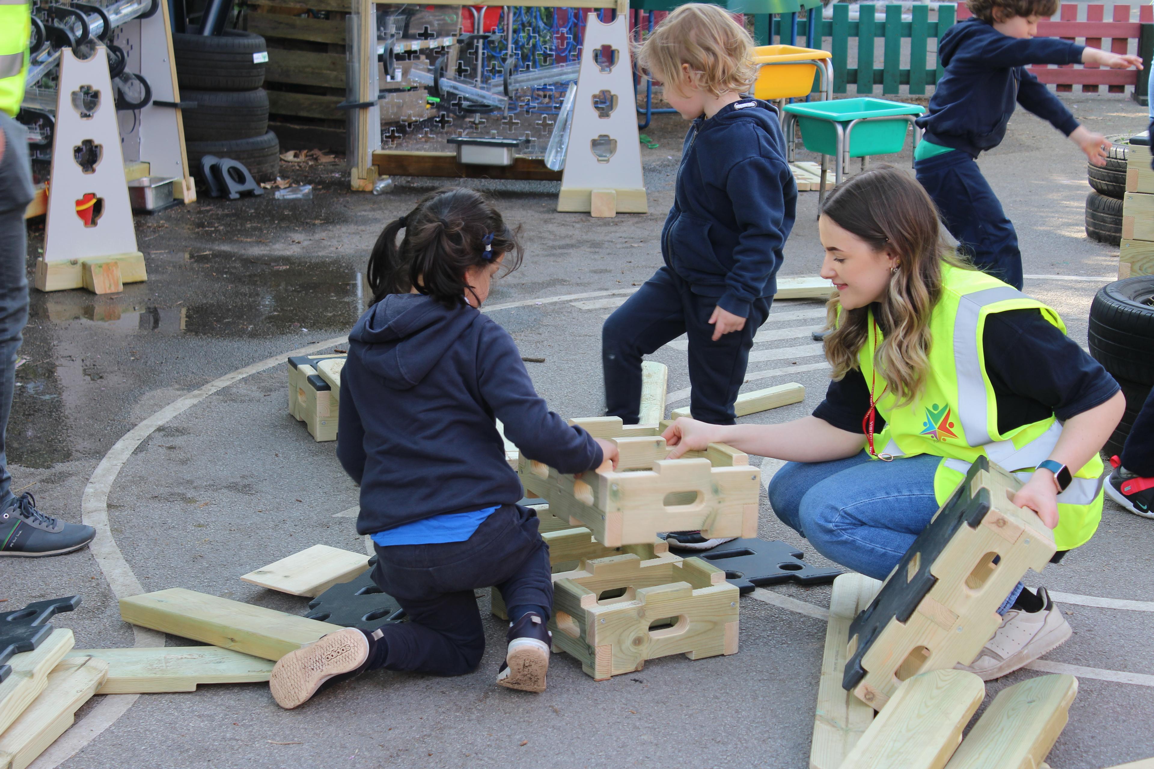 A group of children and an adult making a tower with play builder blocks