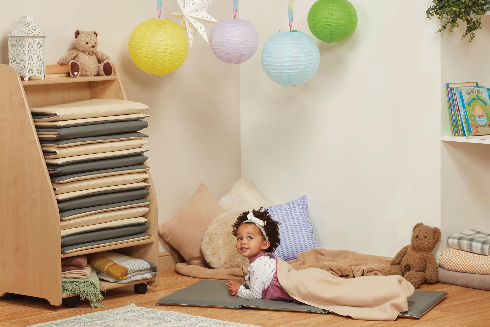 A little girl is lying on a sleep mat next to the Mobile Sleep Mat Store.