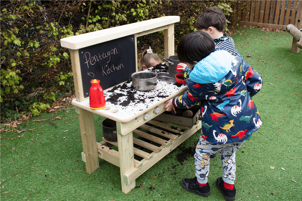 A young boy playing on the low cost mud kitchen in his playground