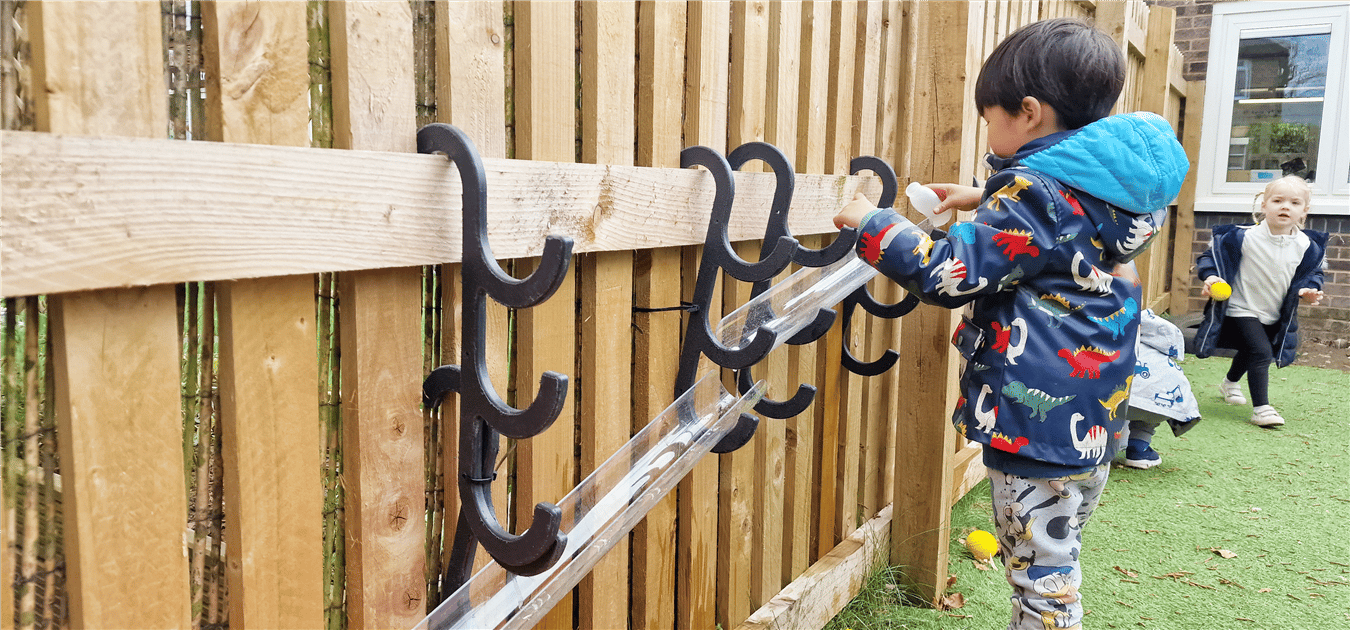 A young boy playing with the water channel hooks that are placed on fencing
