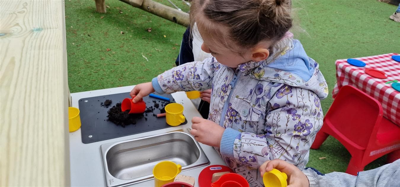 A young girl playing on the mud kitchen for schools