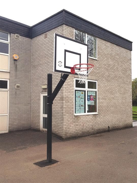 A side view of a adjustable basket ball post, there are no children playing around this piece of equipment.