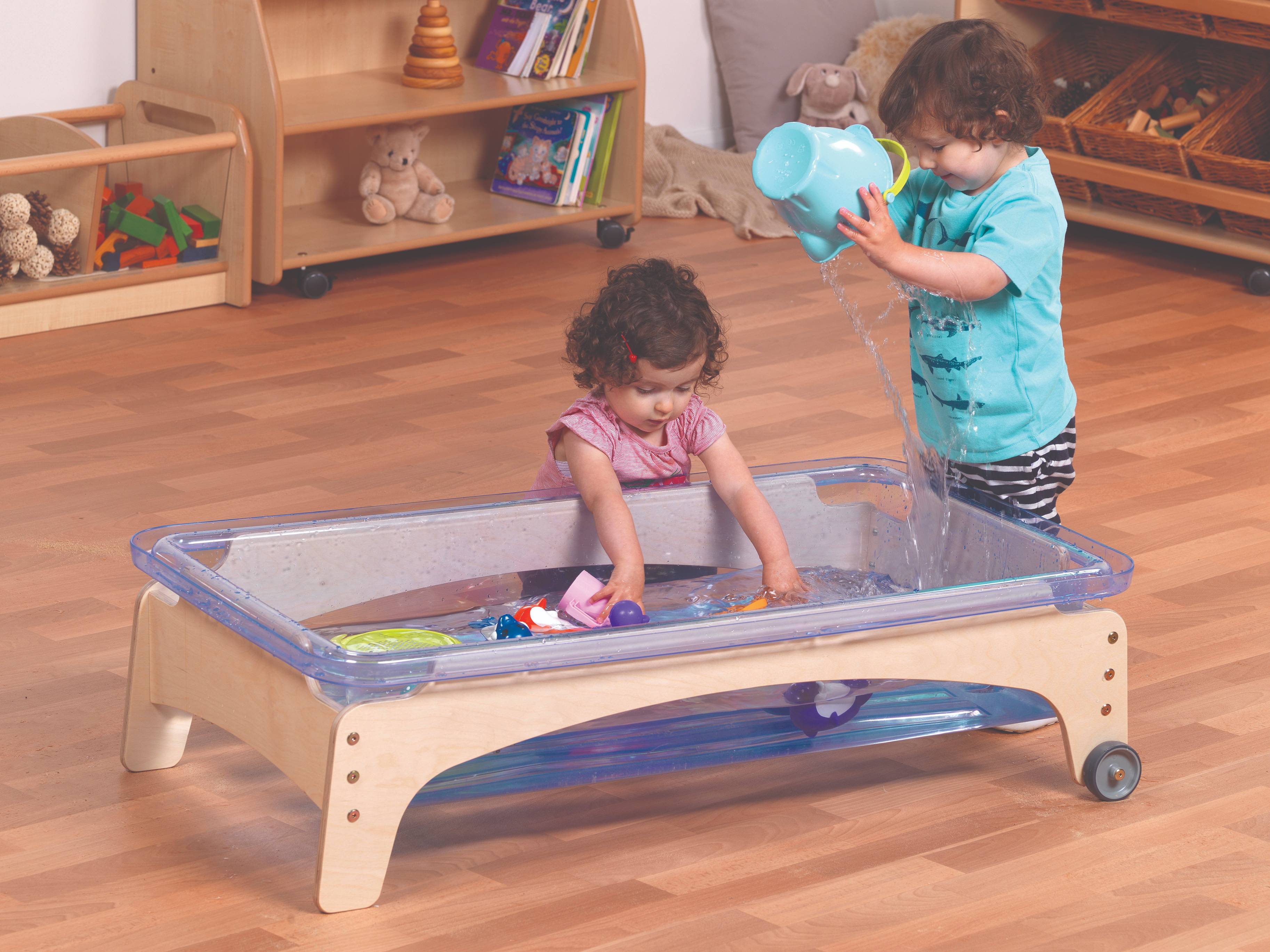 Two toddlers are playing with the Sand & Water Station in a classroom