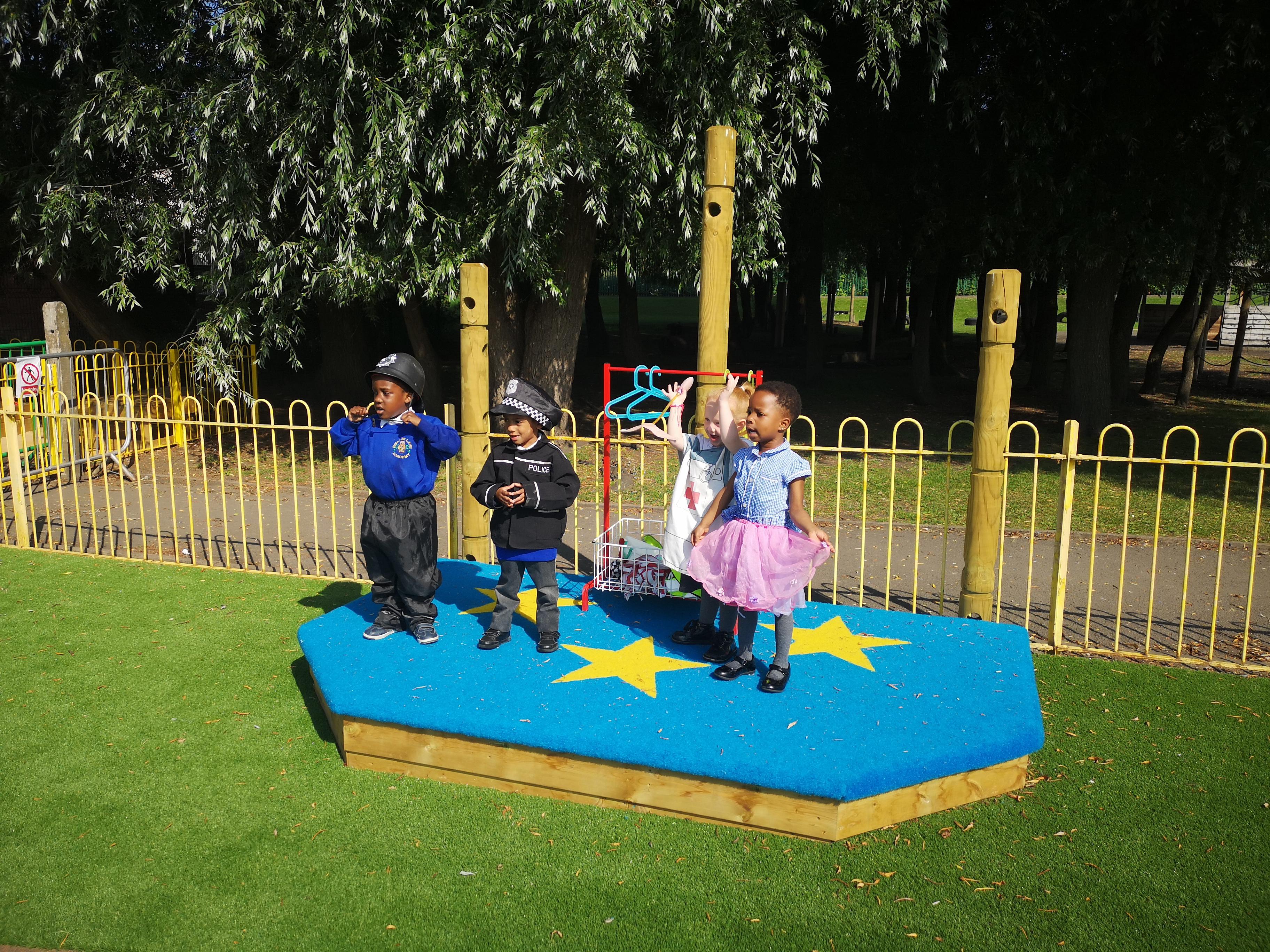 4 young children plying on their performance stage, they are dressed up in fancy dress whilst performing a show.