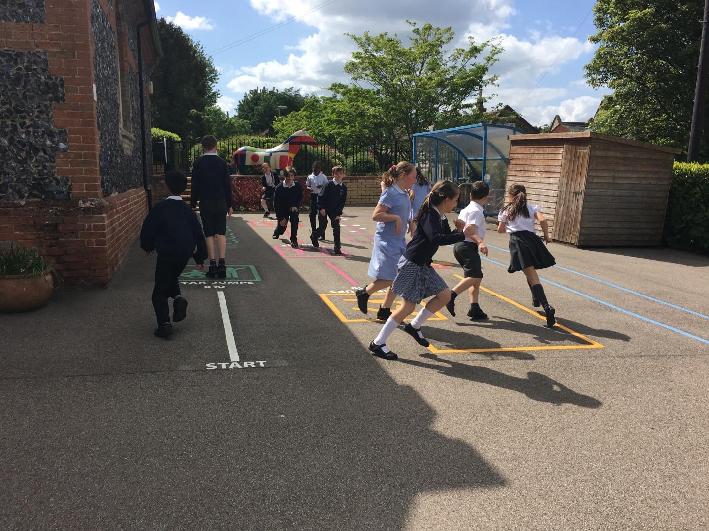 A large group of children are playing with our thermoplastic line markings. A variety of different colours are being used to create the playground. The surface of the play area is tarmac.