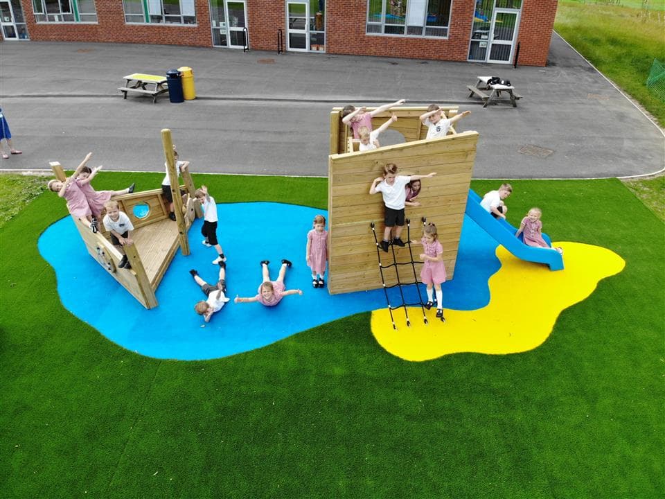16 children playing on our playship, 2 children are lying on the blue wet pour acting as if they are in the water around the ship.