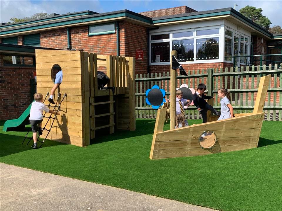 7 children playing on our playship, 1 boy is climbing up the ropes and the rest of the children are playing on or around the ship.