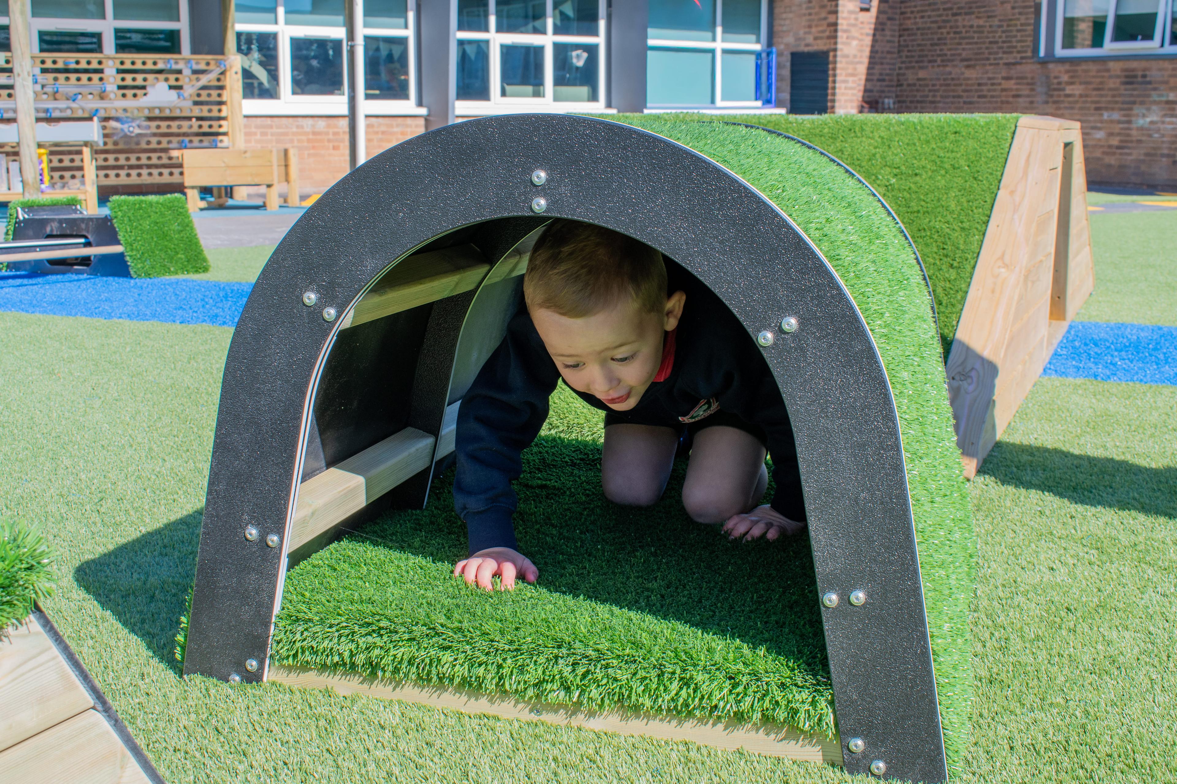 A little boy is crawling through the tunnel block.