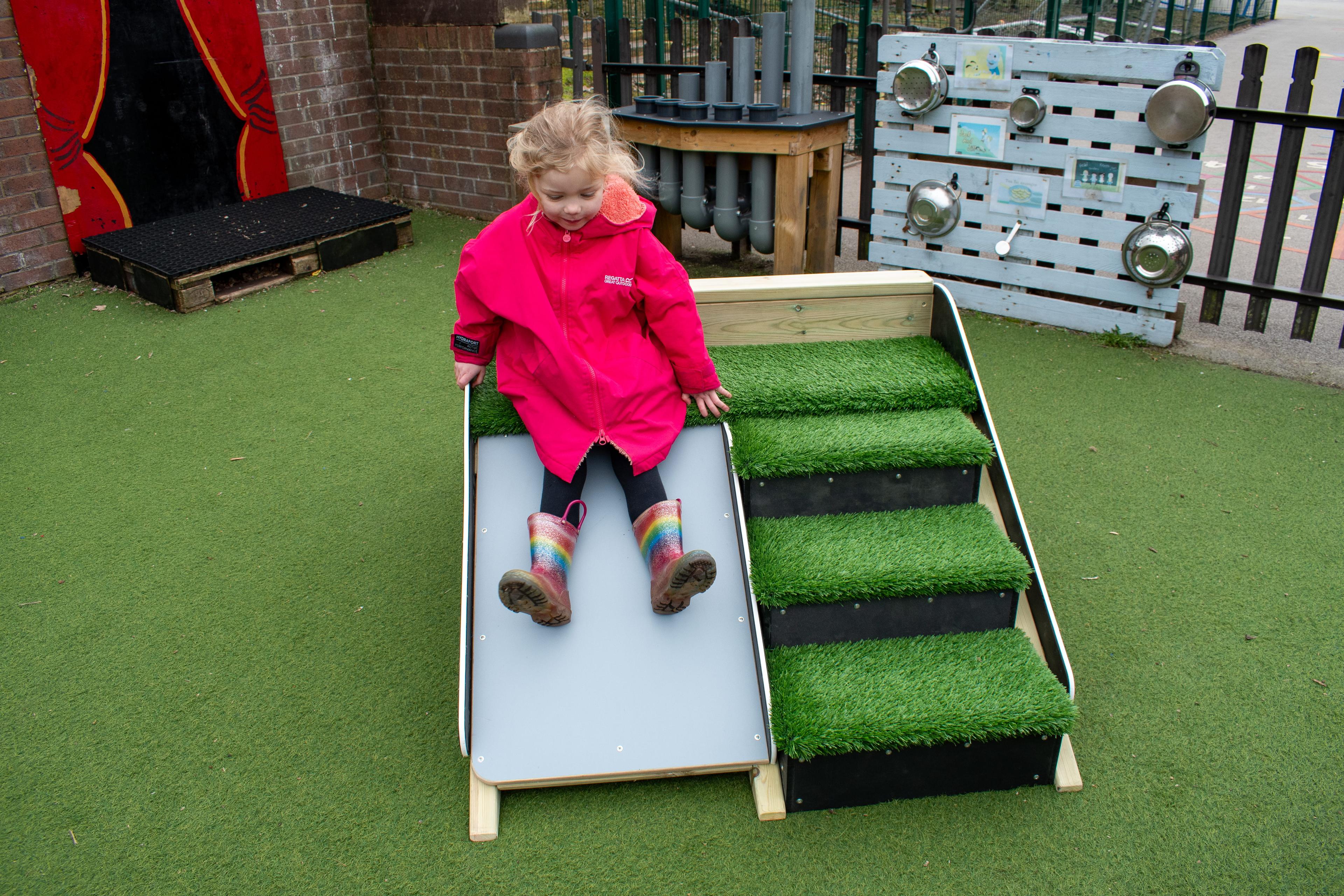 A child sliding down the a-frame, placed on a nursery playground.