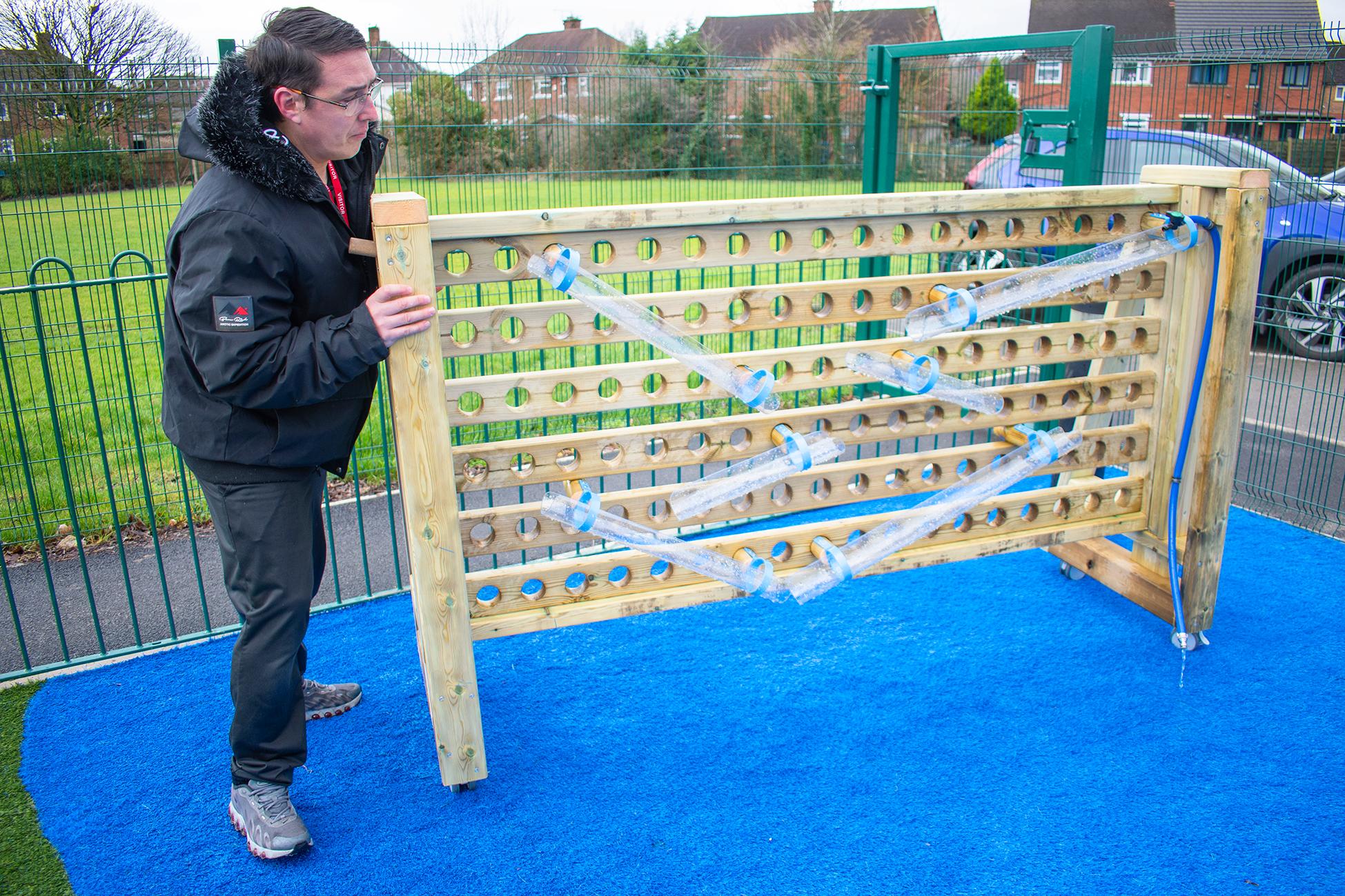 A teacher demonstrating that the movable water wall is a freestanding product and can be wheeled to the nearest water supply
