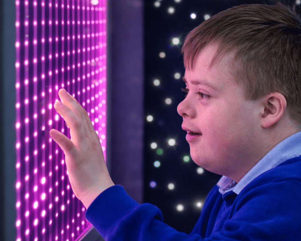 A SEN boy is looking at the infinity LED lights, touching the screen.