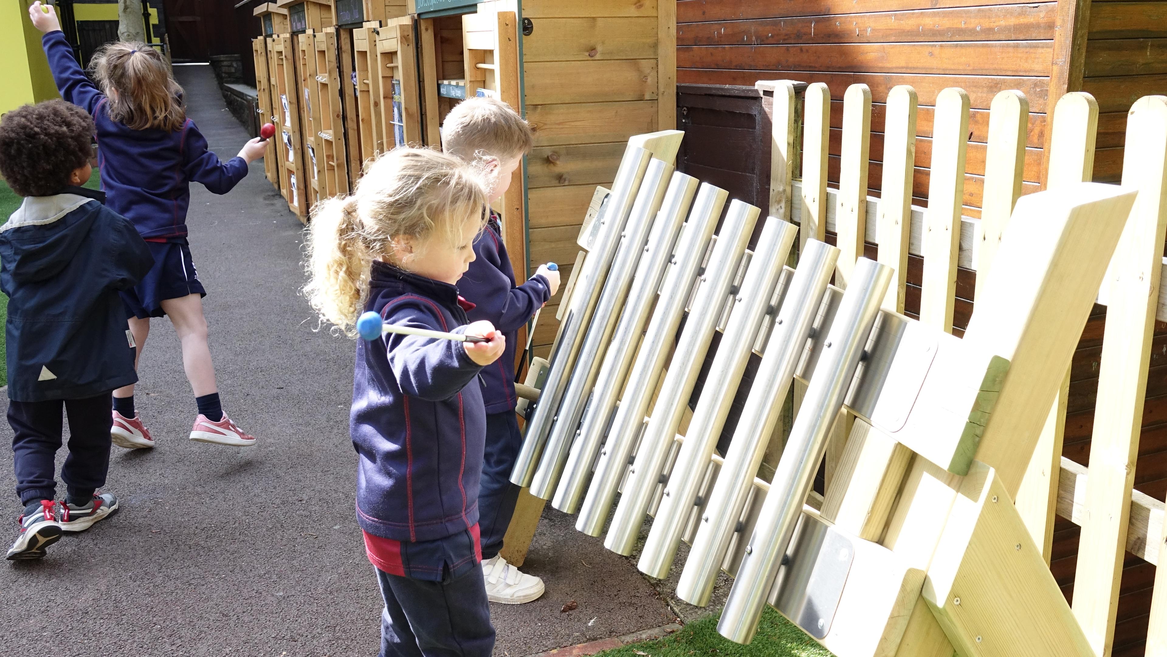 Young girl enjoying musical play on the mini freestanding chimes.