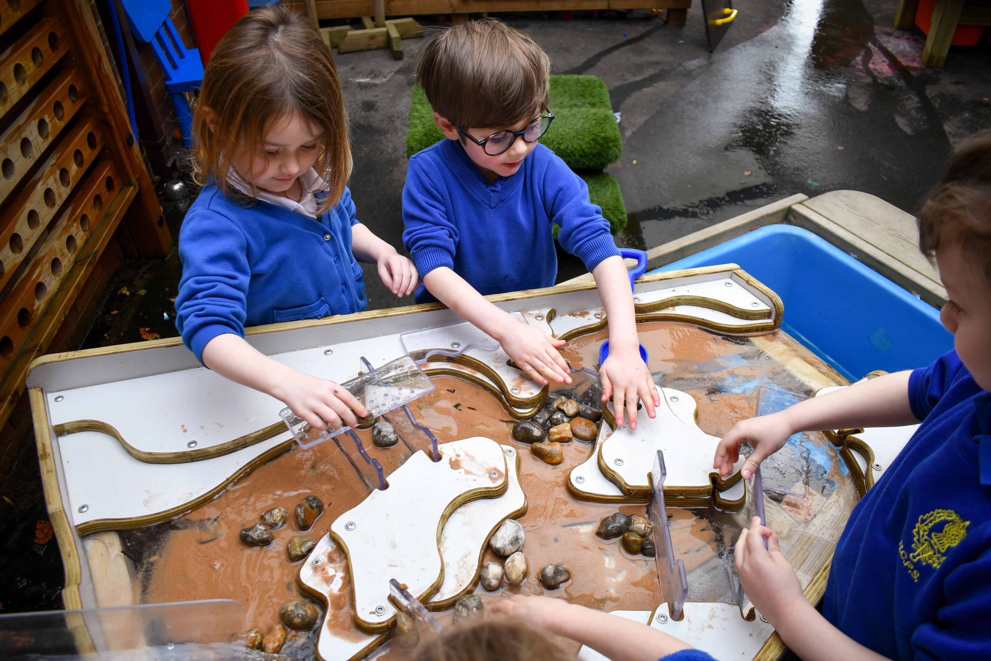 A close up of the damming station being used with the water wall. Three children are moving the dividers to let water flow through