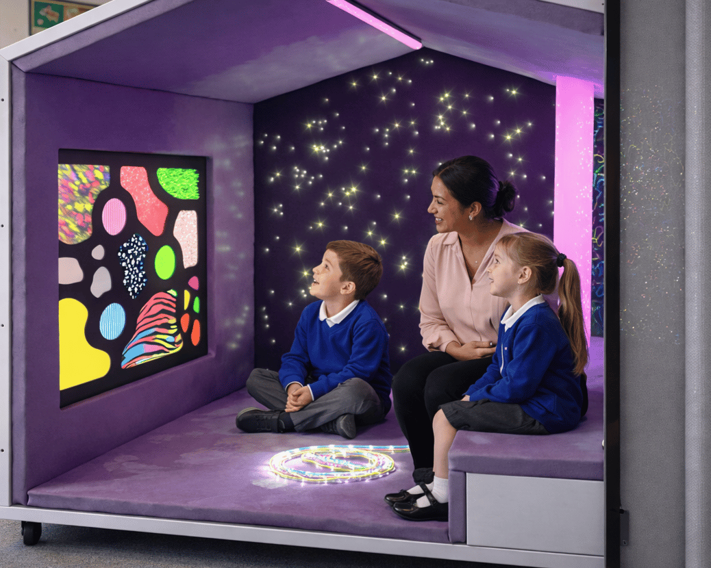 Two children and a teacher are sat within a Sensory Nook, as the Privacy Screen is left open.