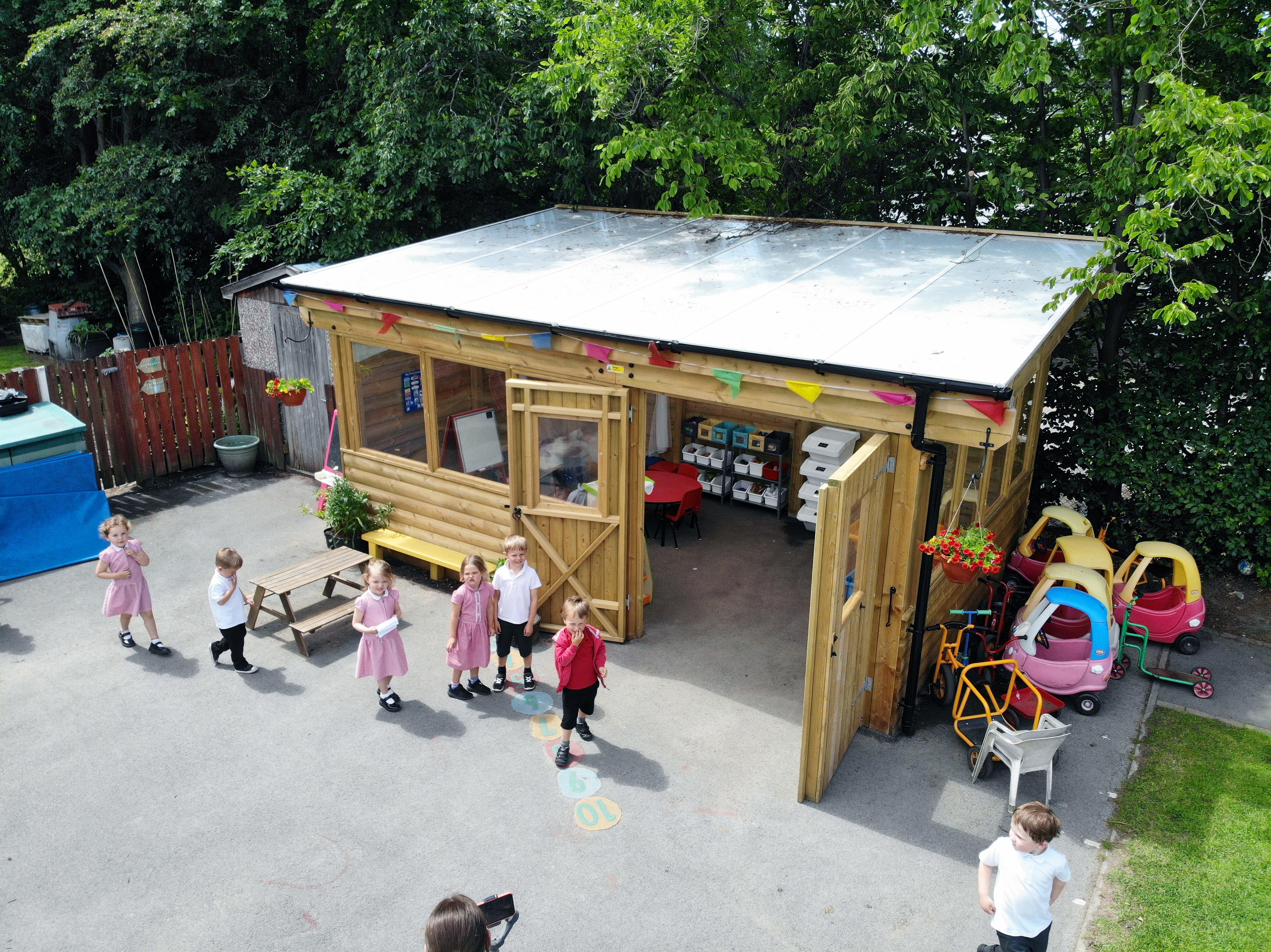 A photo of a bustling playground nearby the timber canopy with doors, cladding and glazing.
