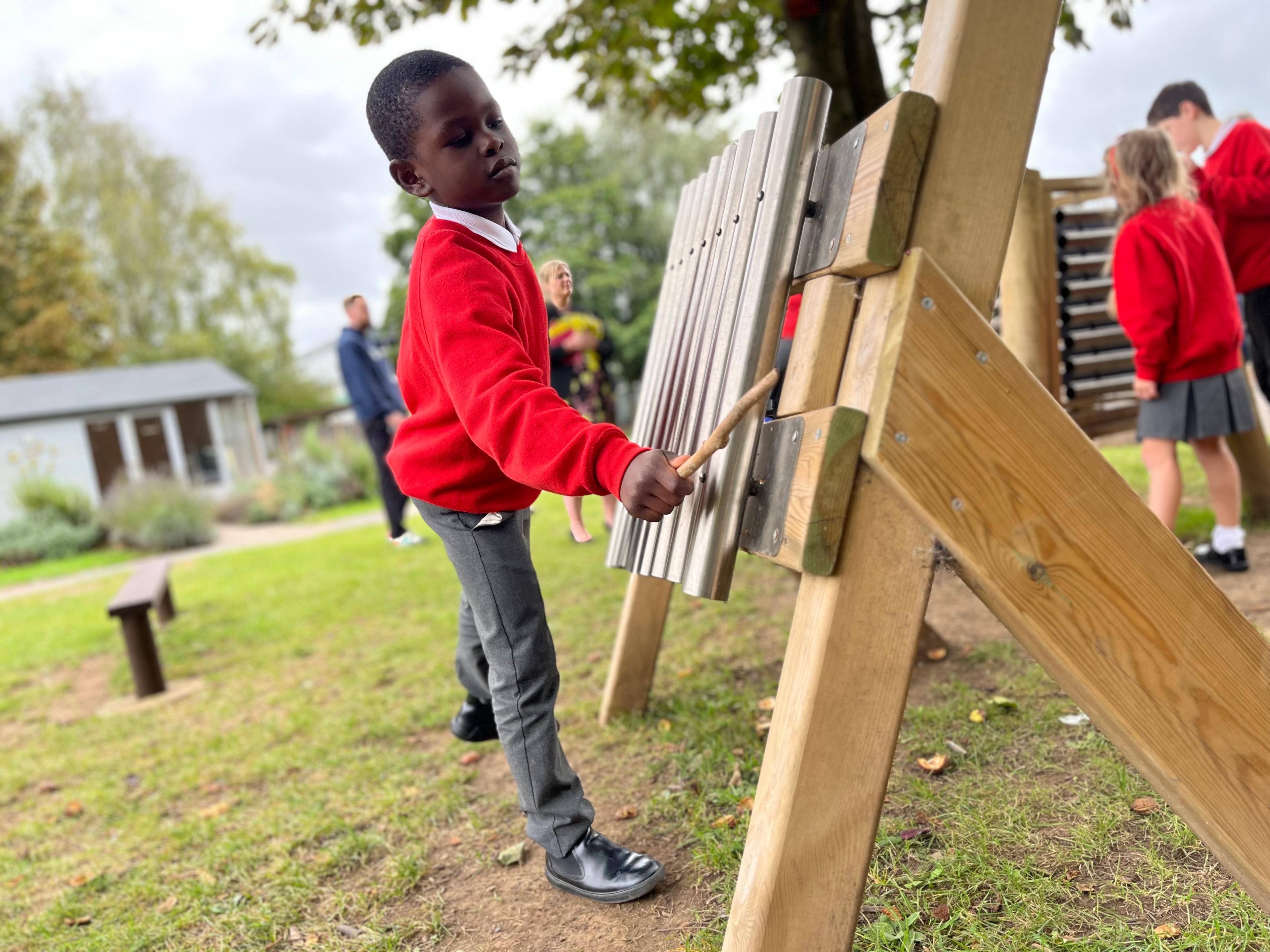 A photo of a child playing the freestanding chimes.