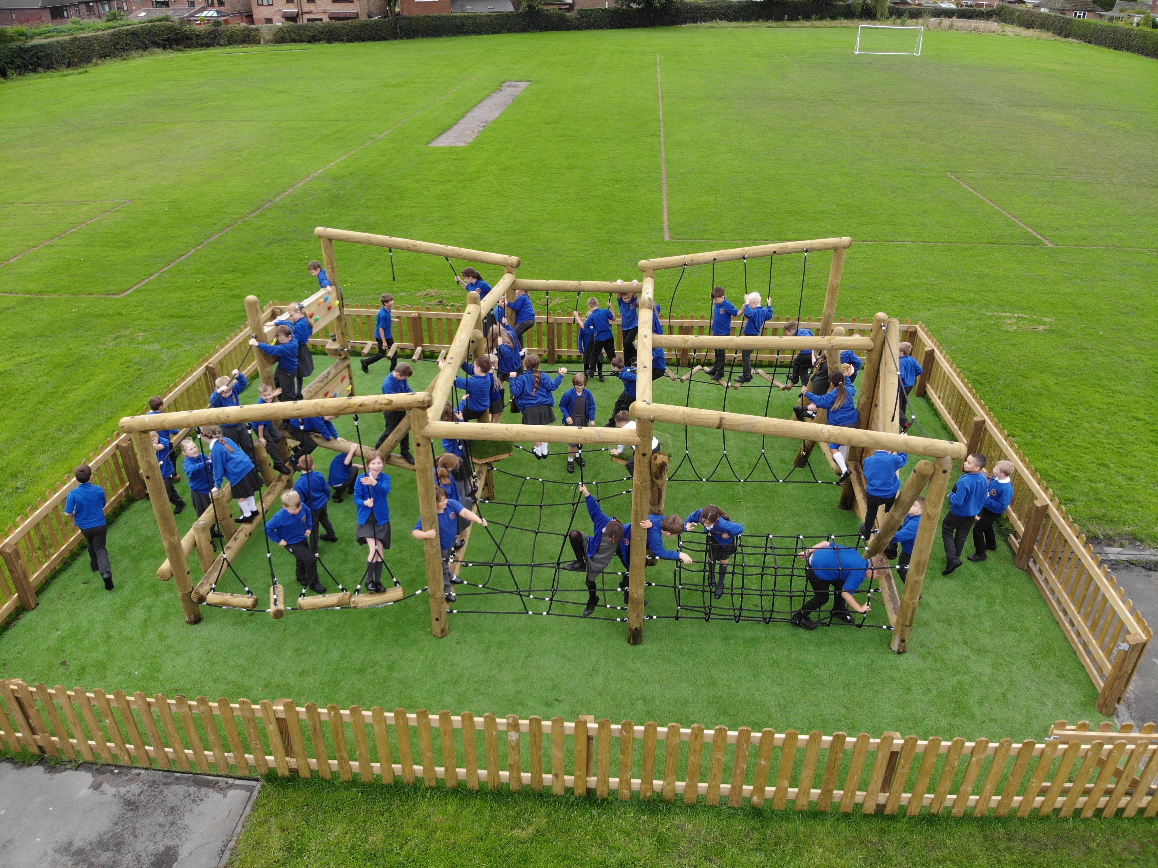 A photo of a large climber play frame surrounded by wooden bow top fencing.