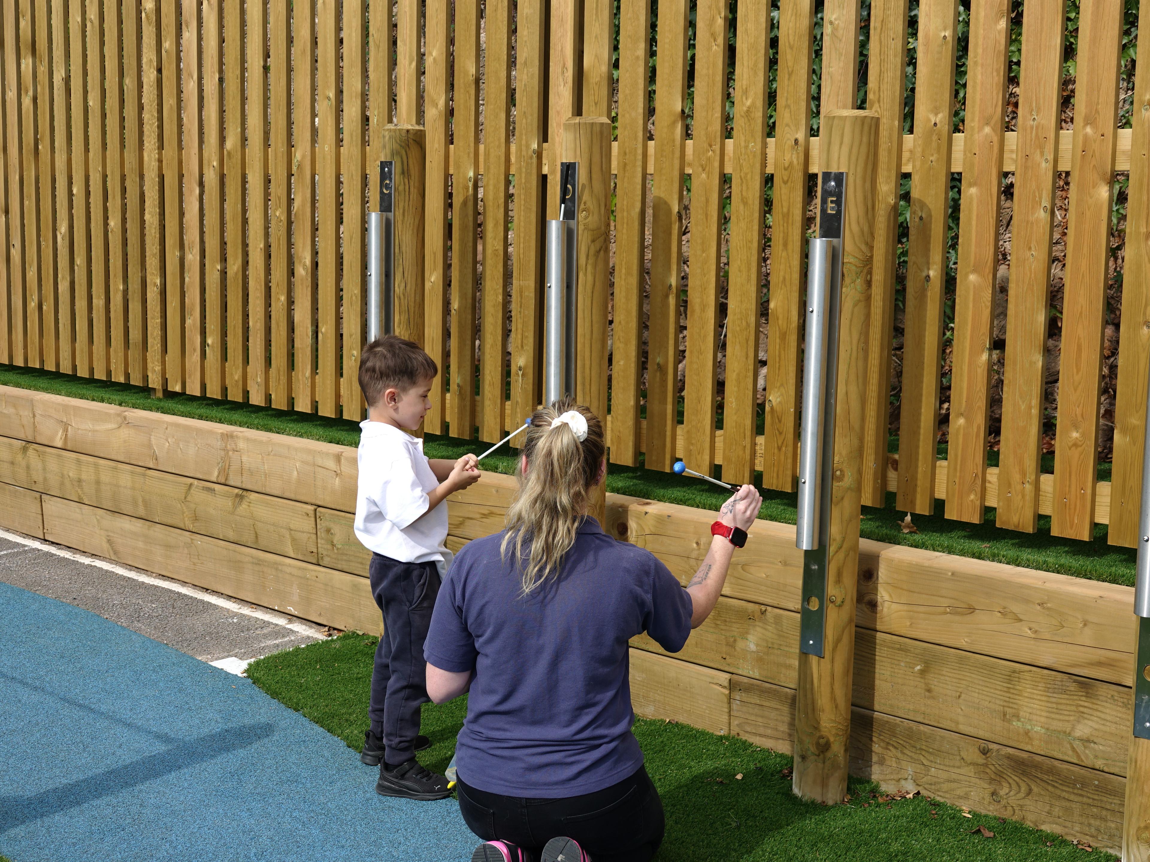 A teacher showing a child how to play the chimes.