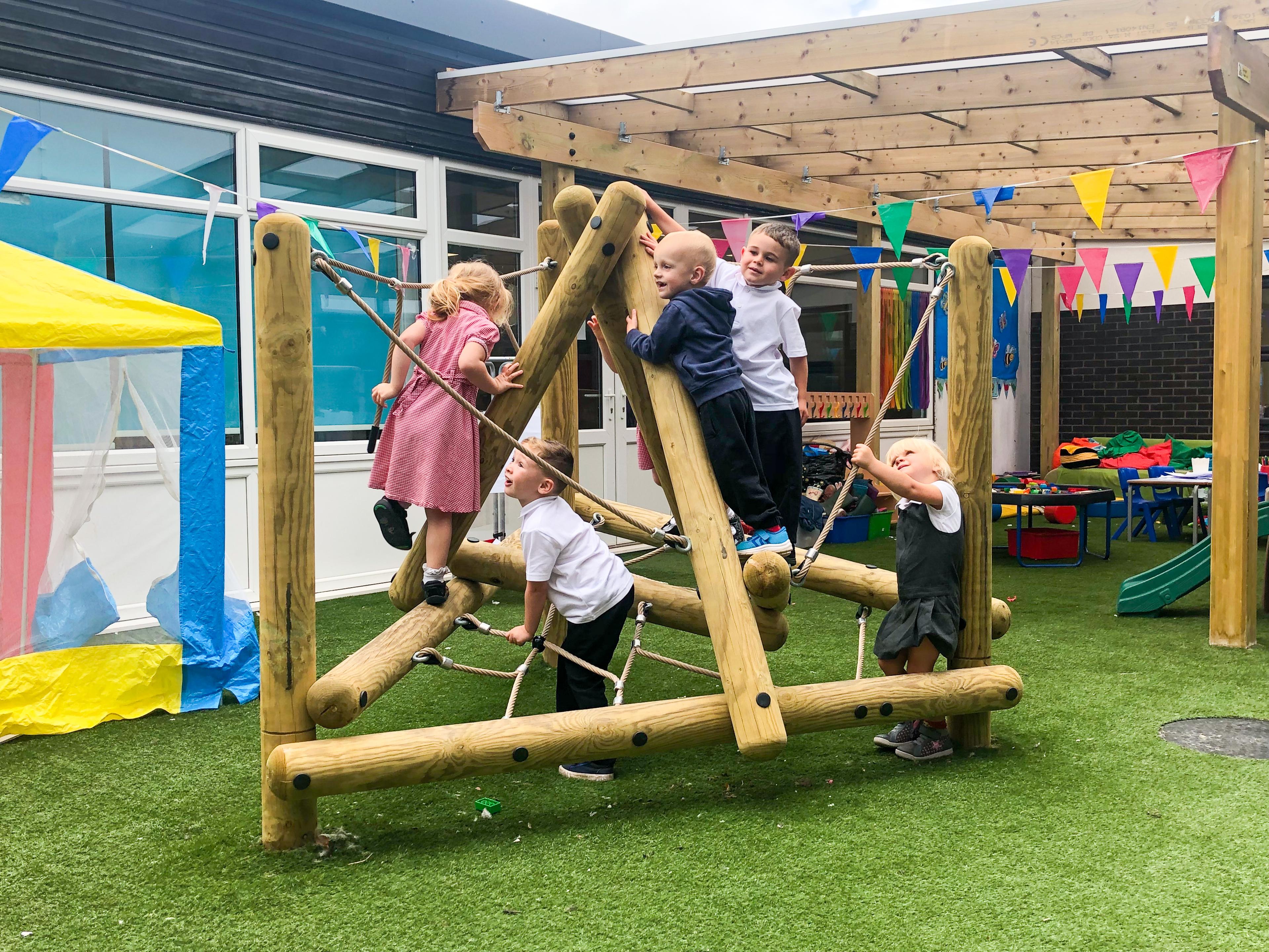 A photo of a group of young children playing on a small climbing frame.