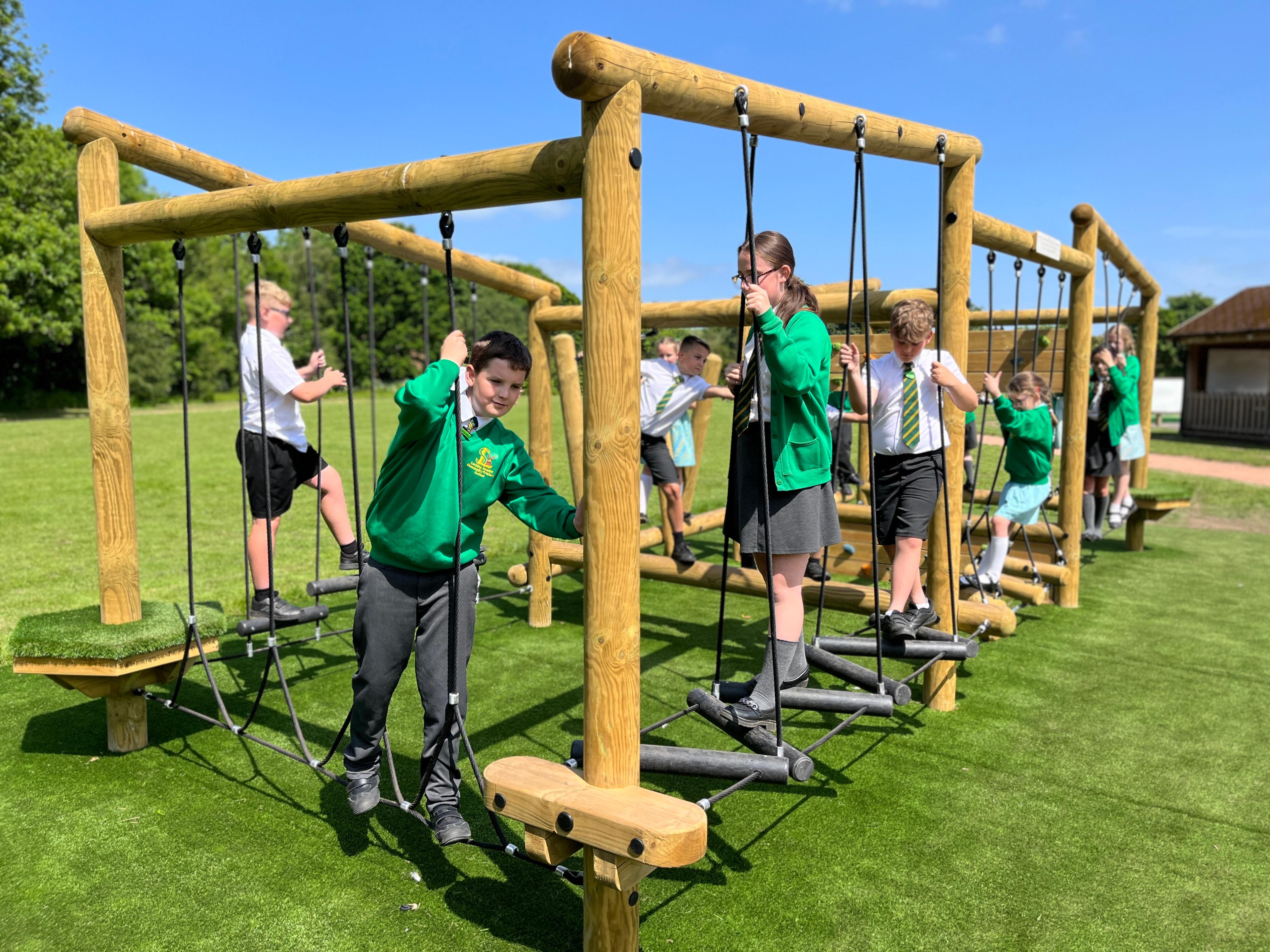 A group of key stage 2 children playing on a Kielder Forest Circuit playframe.